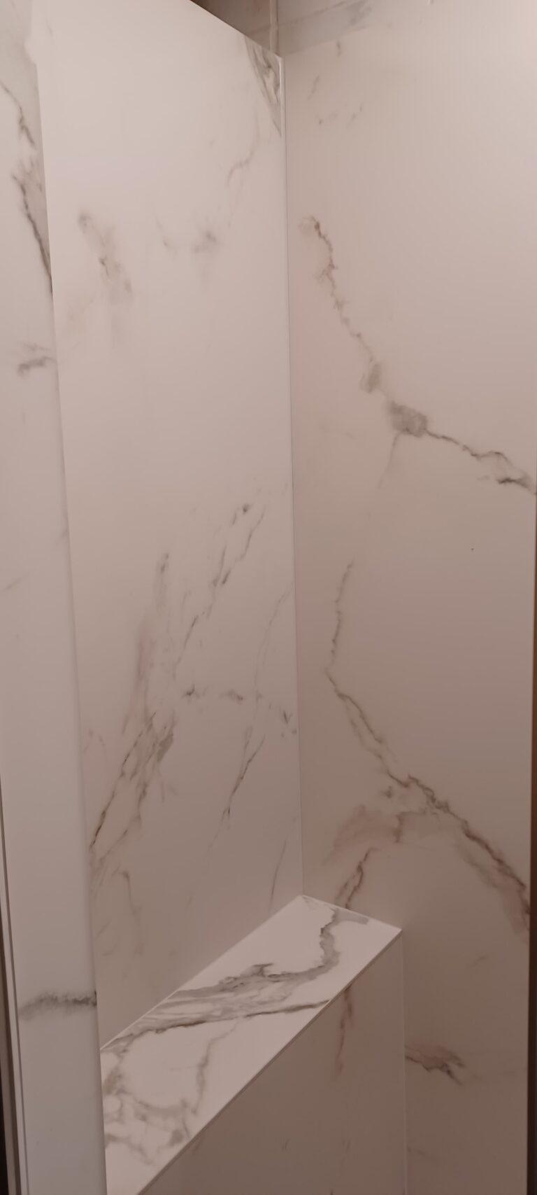 eine neu verkleidete Duschkabine mit Keramikplatte in Marmoroptik