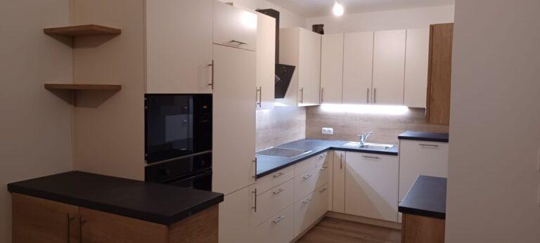 Moderne Küche mit weißen Fronten, schwarzer Arbeitsfläche und Holzelementen